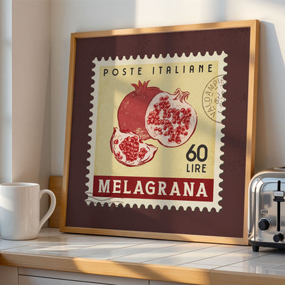 a framed vintage postage stamp with an illustration of pomegranates, placed on a counter next to a toaster.