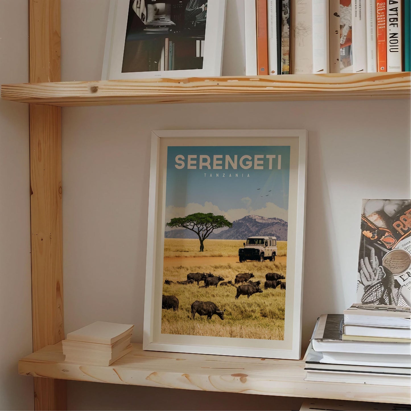 a framed poster of a safari scene in Tanzania, with a truck and a herd of wildebeest in the foreground.