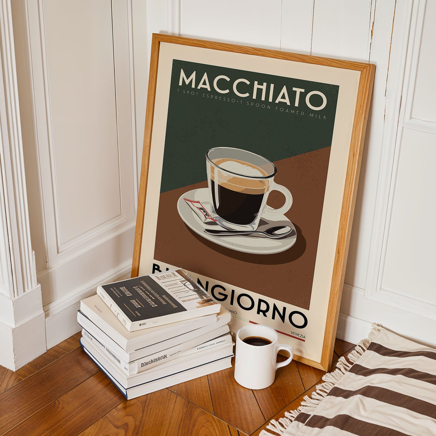 a framed poster of a cup of coffee with the text "MACCHIATO" and "I SPOT ESPRESSO! 1 SPON FOAMED MILK" on it, along with a stack of books and a white mug on the floor.