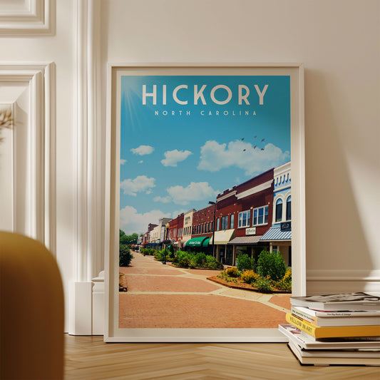 A framed poster of a street scene in Hickory, North Carolina, with colorful buildings and a clear blue sky.