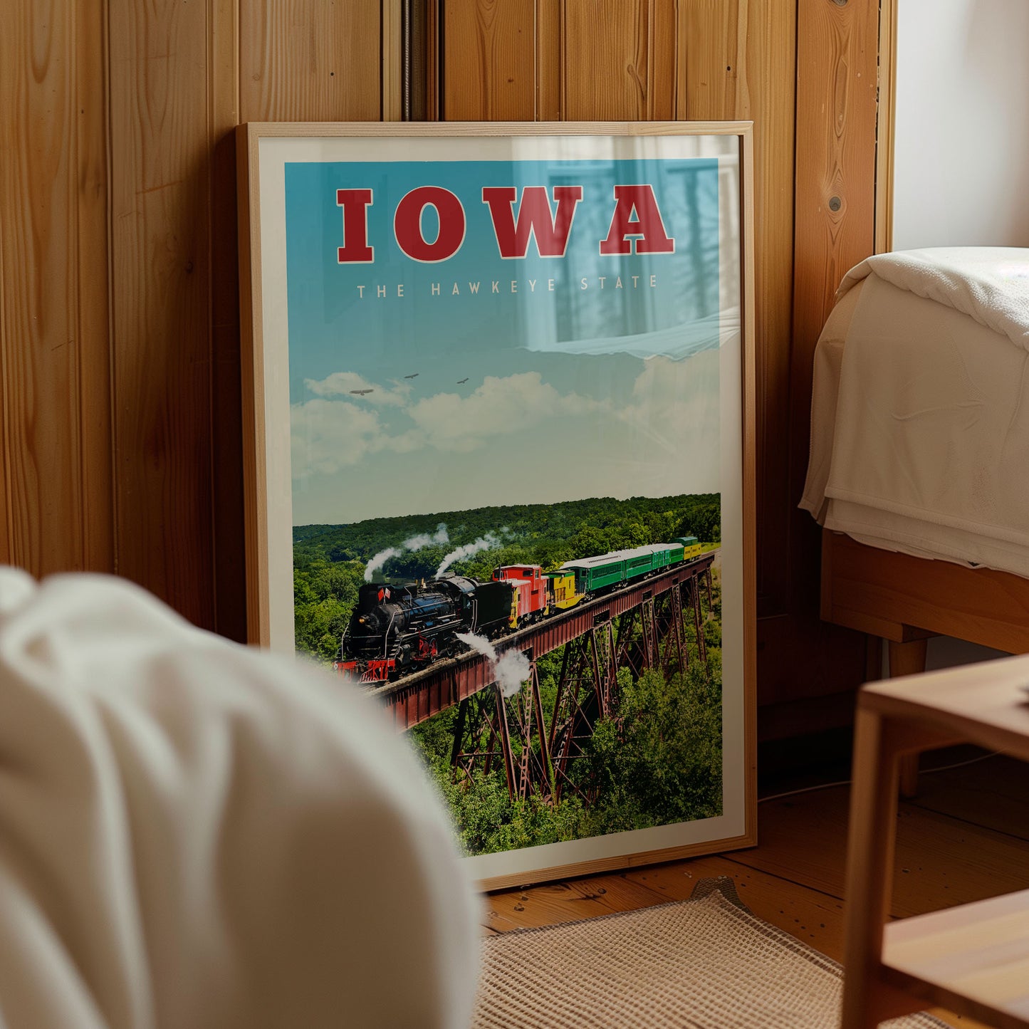 a framed poster of a steam train on a bridge, with the word "IOWA" prominently displayed.