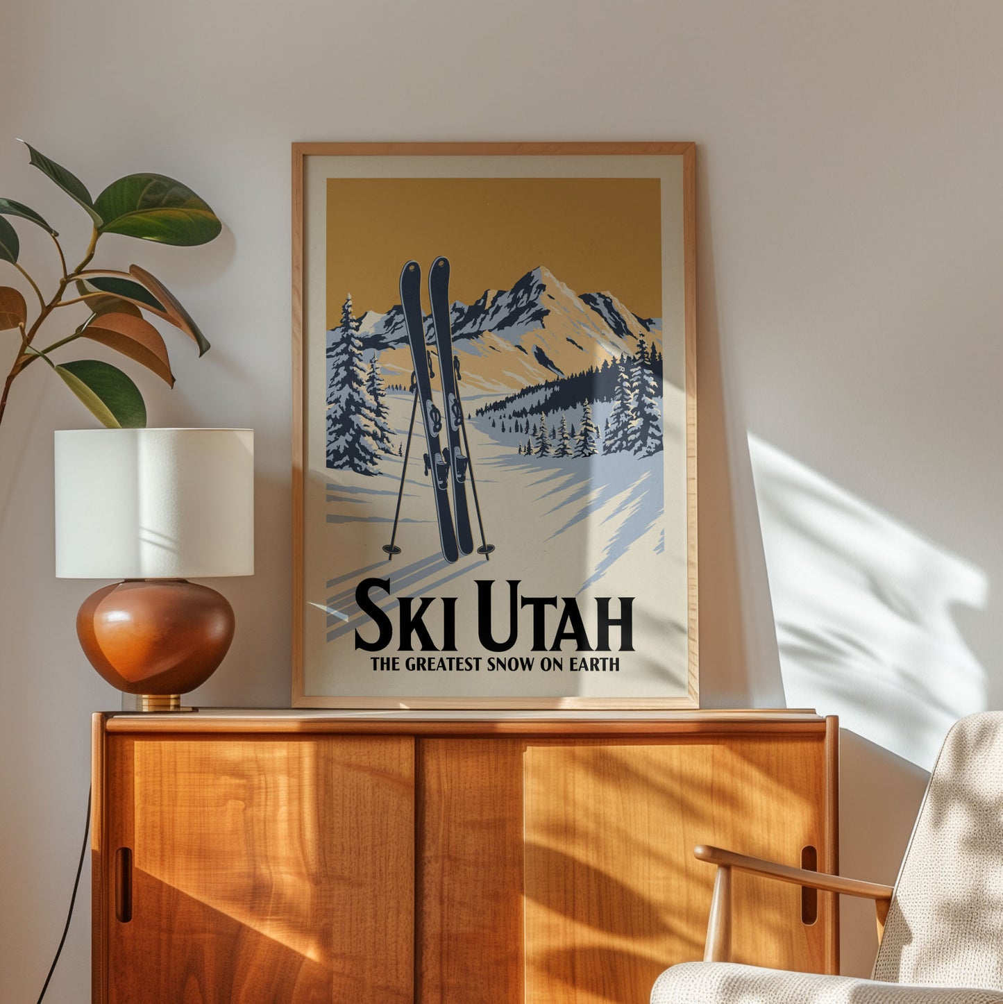 A framed poster of a snowy mountain landscape with skis, hanging on a wall above a wooden cabinet.