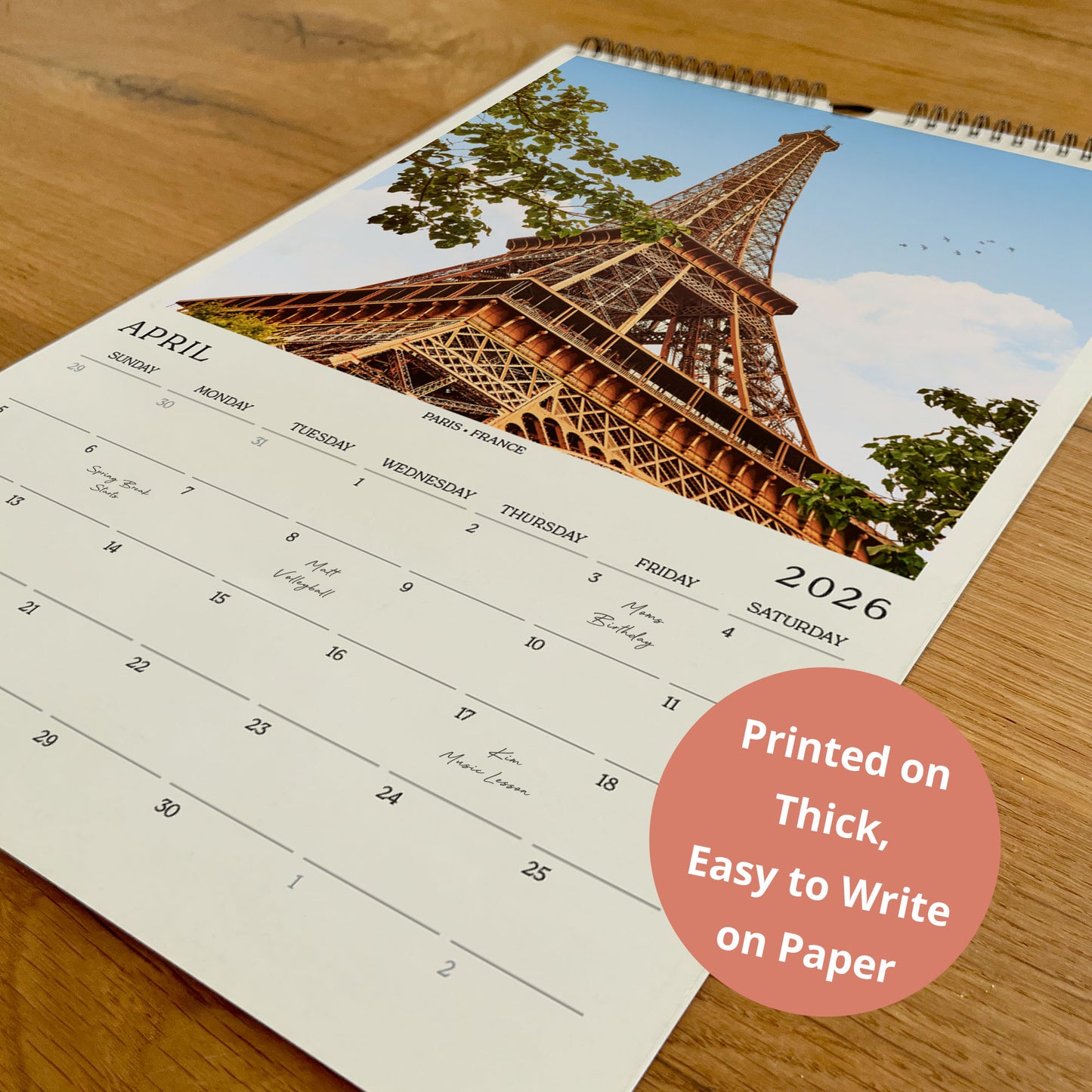 A wall calendar with a photo of the Eiffel Tower on the cover, and the text "Printed on Thick, Easy to Write on Paper" in the bottom right corner.