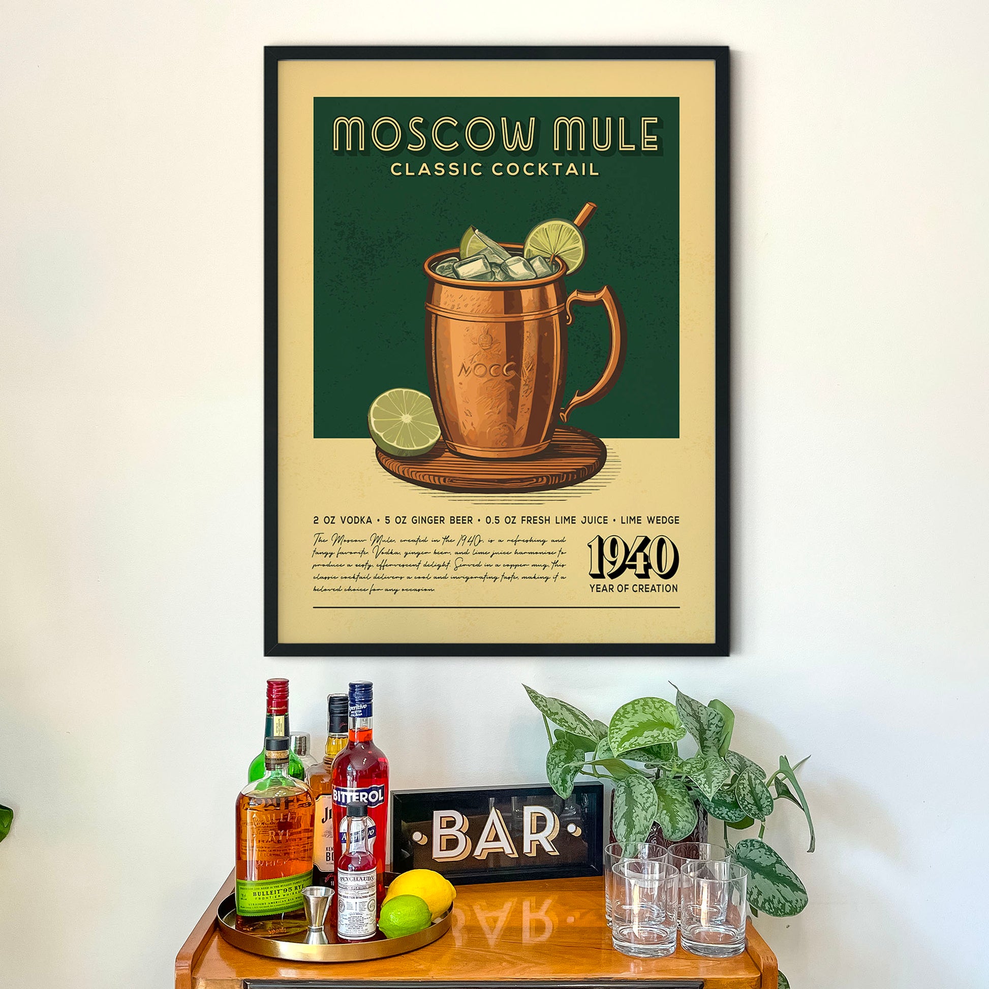 a framed poster of a Moscow Mule cocktail hanging on a wall above a wooden bar counter with various liquor bottles and glasses.