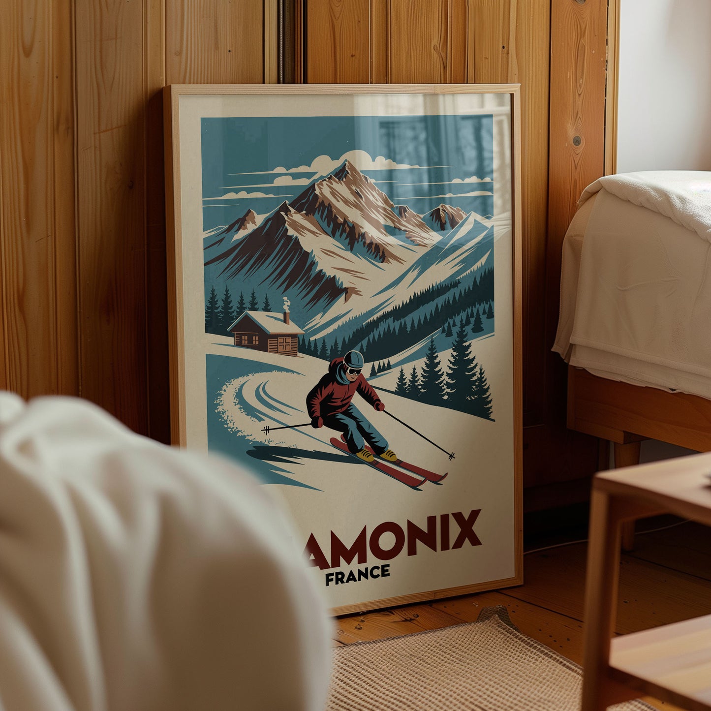 A framed poster of a skier in a red jacket and blue pants, skiing down a snowy mountain with a cabin in the background, is displayed in a room with wooden walls.