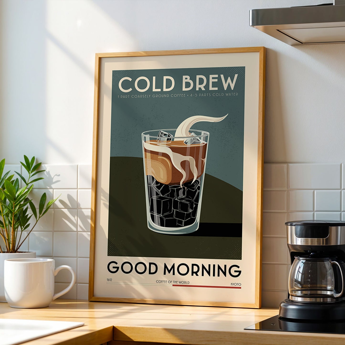 a framed poster of a glass of cold brew coffee with ice cubes, placed on a kitchen counter next to a coffee maker.