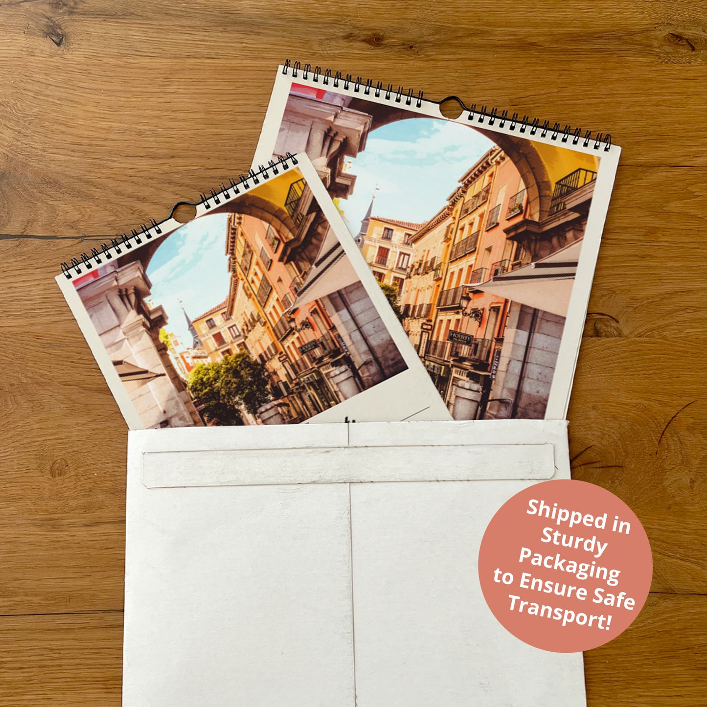 two spiral-bound photo albums placed inside a white envelope on a wooden surface.