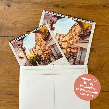 two spiral-bound photo albums placed inside a white envelope on a wooden surface.