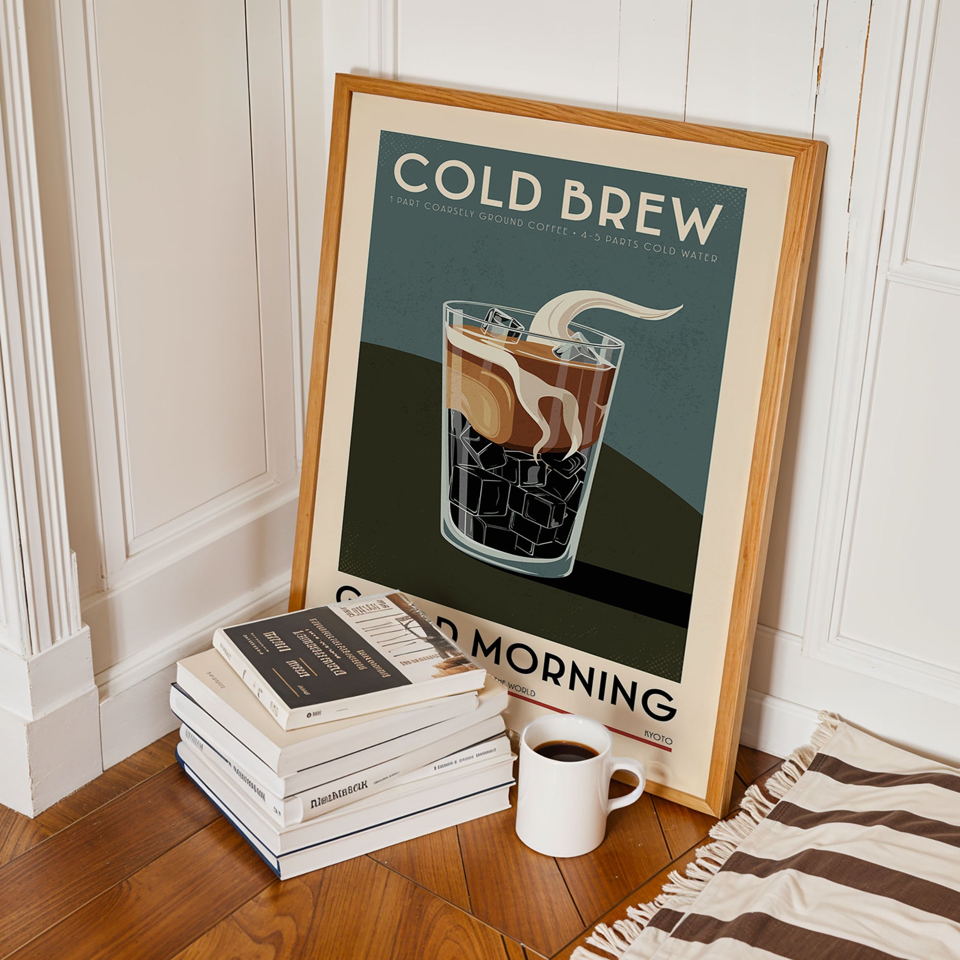 a framed poster of a glass of cold brew coffee with ice cubes, accompanied by a stack of books and a cup of coffee on a wooden floor.