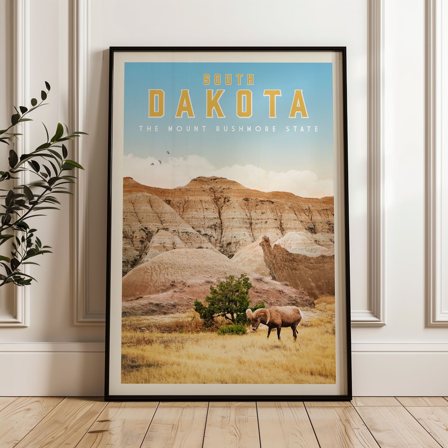 A framed poster of the scenic landscape of South Dakota, featuring a mountain range, a grazing animal, and a clear blue sky.