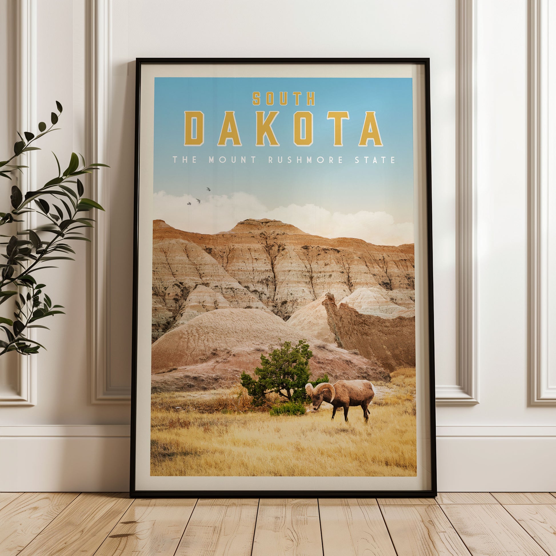A framed poster of the scenic landscape of South Dakota, featuring a mountain range, a grazing animal, and a clear blue sky.