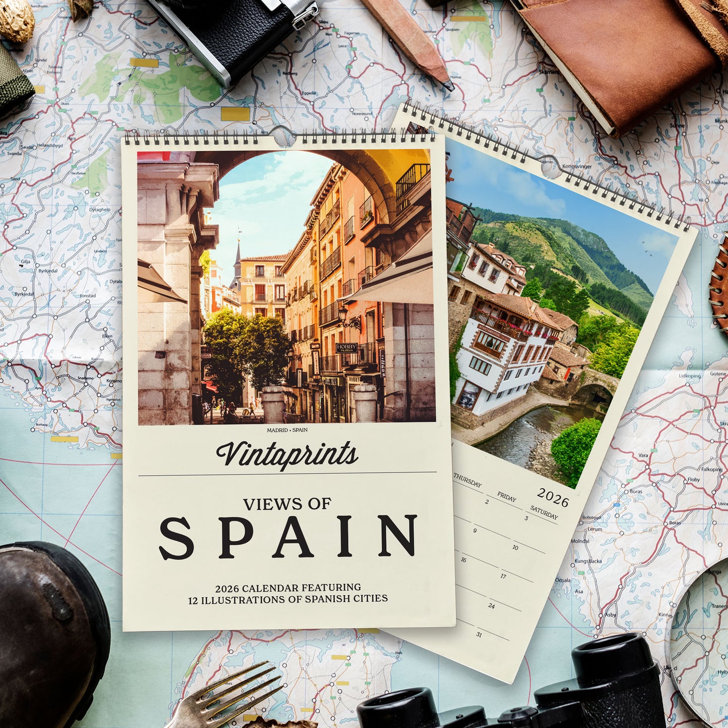 a calendar with a photo of a city and a map of Spain, along with various travel-related items such as a camera, a magnifying glass, and a pocket watch.