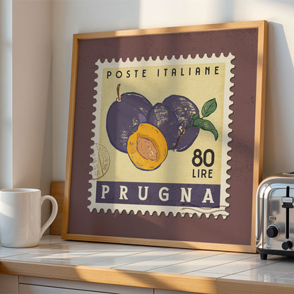 a framed stamp-like artwork depicting plums and a toaster on a kitchen counter.