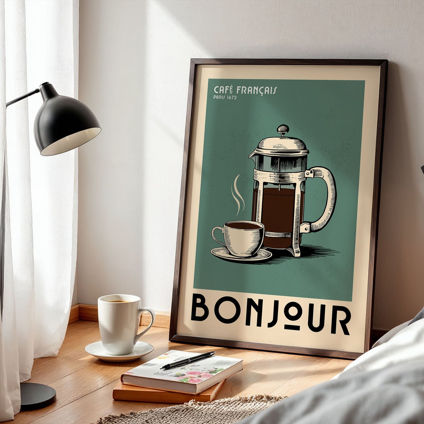 a framed poster of a French coffee pot, a cup of coffee, and the word " bonjour" on a wooden floor. There is also a lamp, a book, and a notebook on the floor next to the poster.