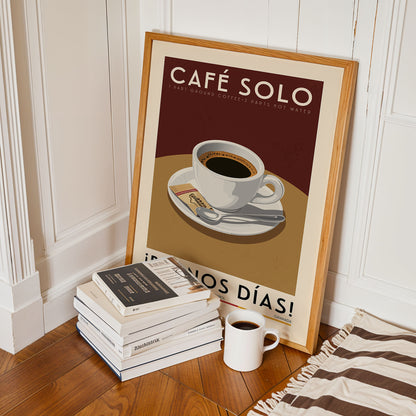 A framed poster of a cup of coffee on a table, surrounded by a stack of books and a white mug, all placed on a wooden floor.