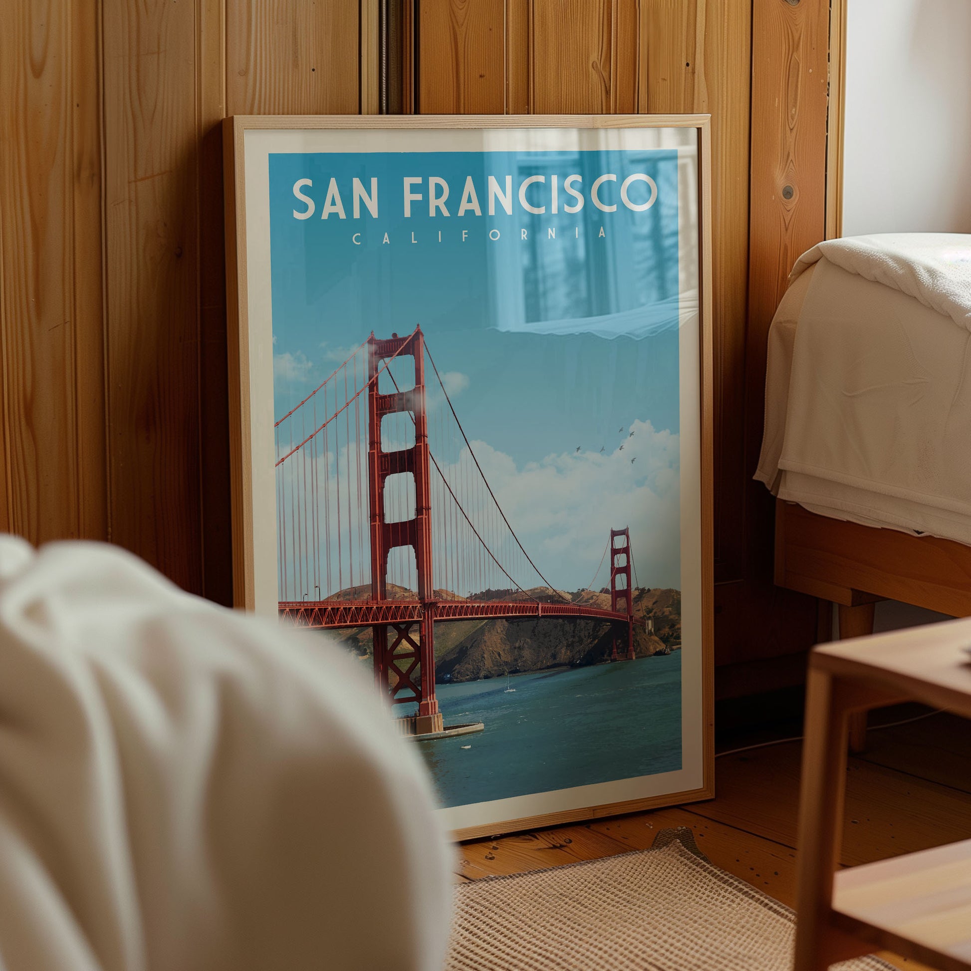 A framed poster of the Golden Gate Bridge in San Francisco, California, is displayed in a room with wooden walls.