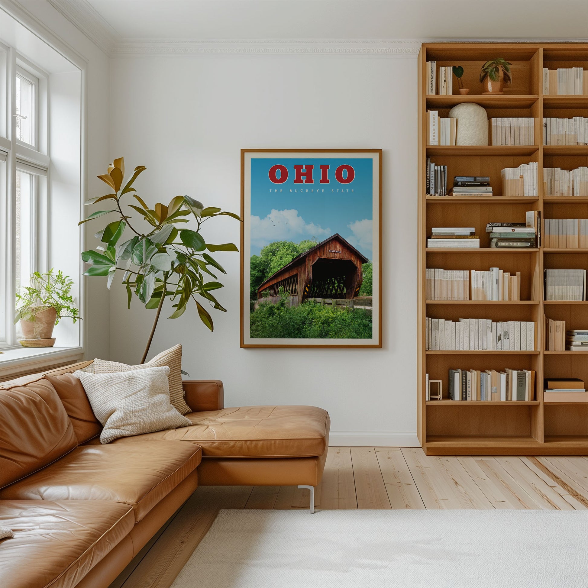 a cozy living room with a brown leather sofa, a large bookshelf filled with books, and a framed poster of a red barn with a tree in the background.