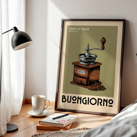 a framed poster of a coffee grinder with the text "Caffè d'Italia" and "Milano 1679" on it, along with the word "BONIGIORNO" below. The poster is displayed on a wooden floor next to a lamp, a cup of coffee, and a book.