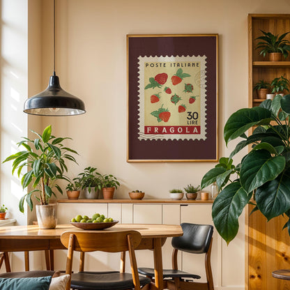 a cozy dining area with a wooden table, chairs, and a potted plant. A framed stamp with a strawberry design hangs on the wall above the table, and a hanging light fixture illuminates the space.