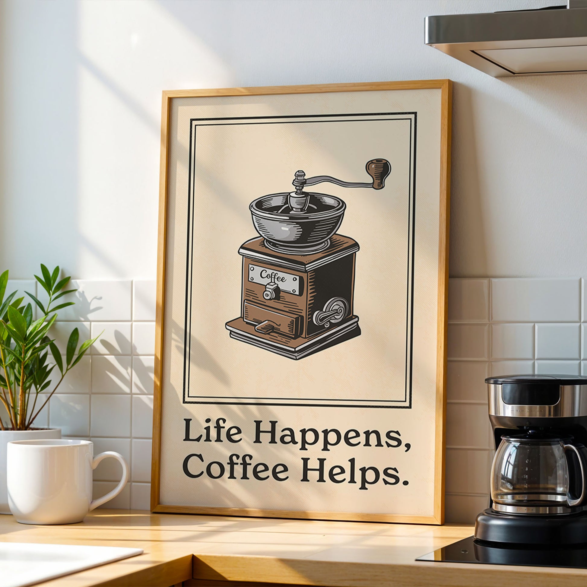 A framed illustration of a coffee grinder is displayed on a kitchen counter, accompanied by the text "Life Happens, Coffee Helps."