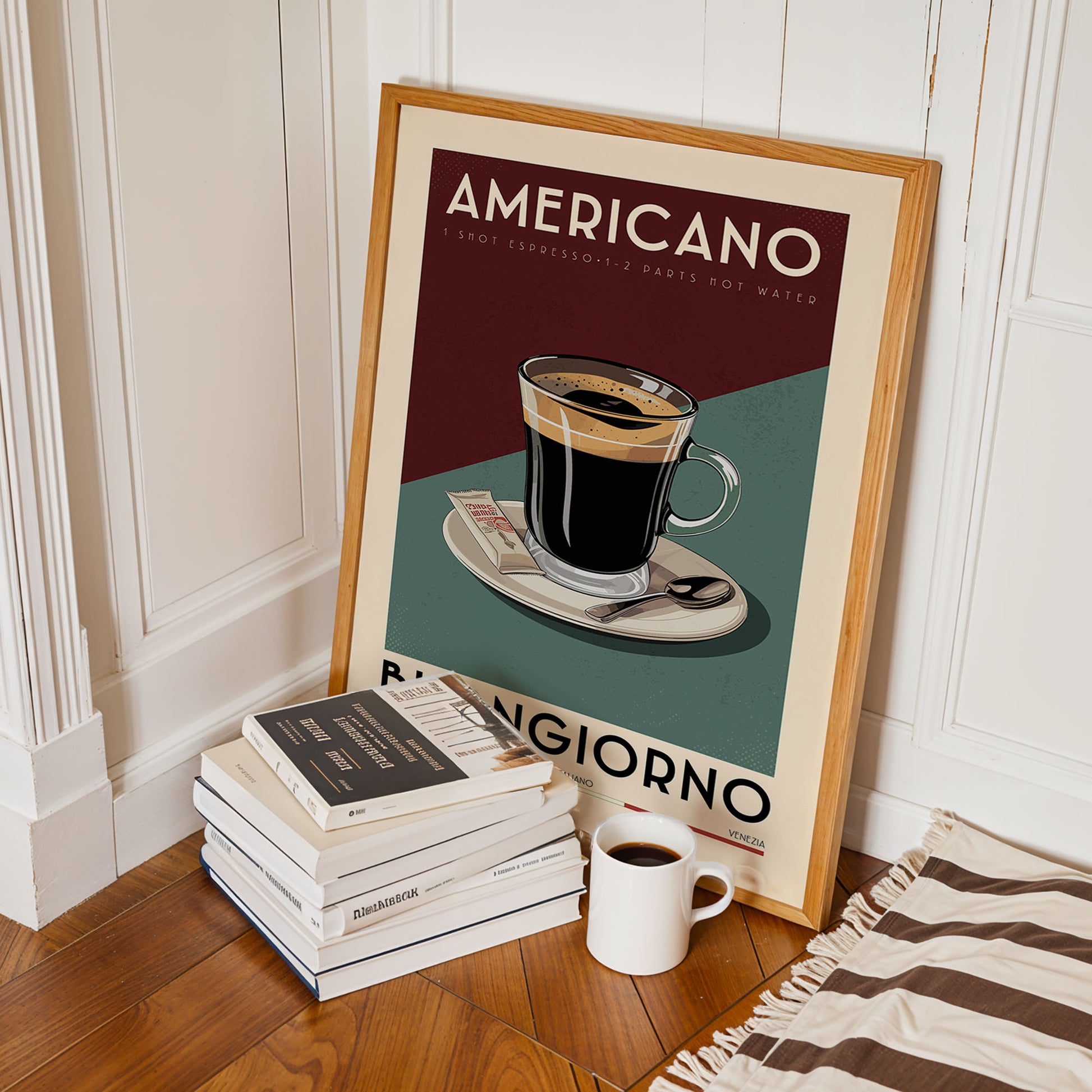 A framed poster of an americano coffee cup is leaning against a white wall, with a stack of books and a white mug on the floor in front of it.