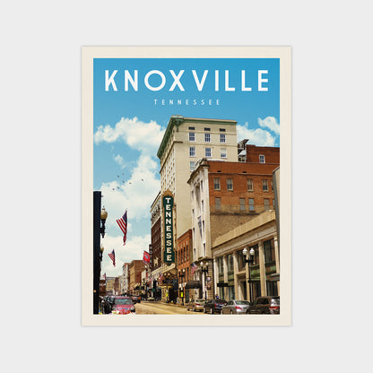 a city street in Knoxville, Tennessee, with tall buildings, cars, and people walking on the sidewalks.