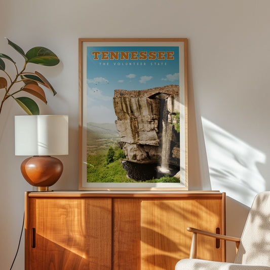 a framed poster of a waterfall in Tennessee, with a wooden cabinet and a lamp in the foreground.