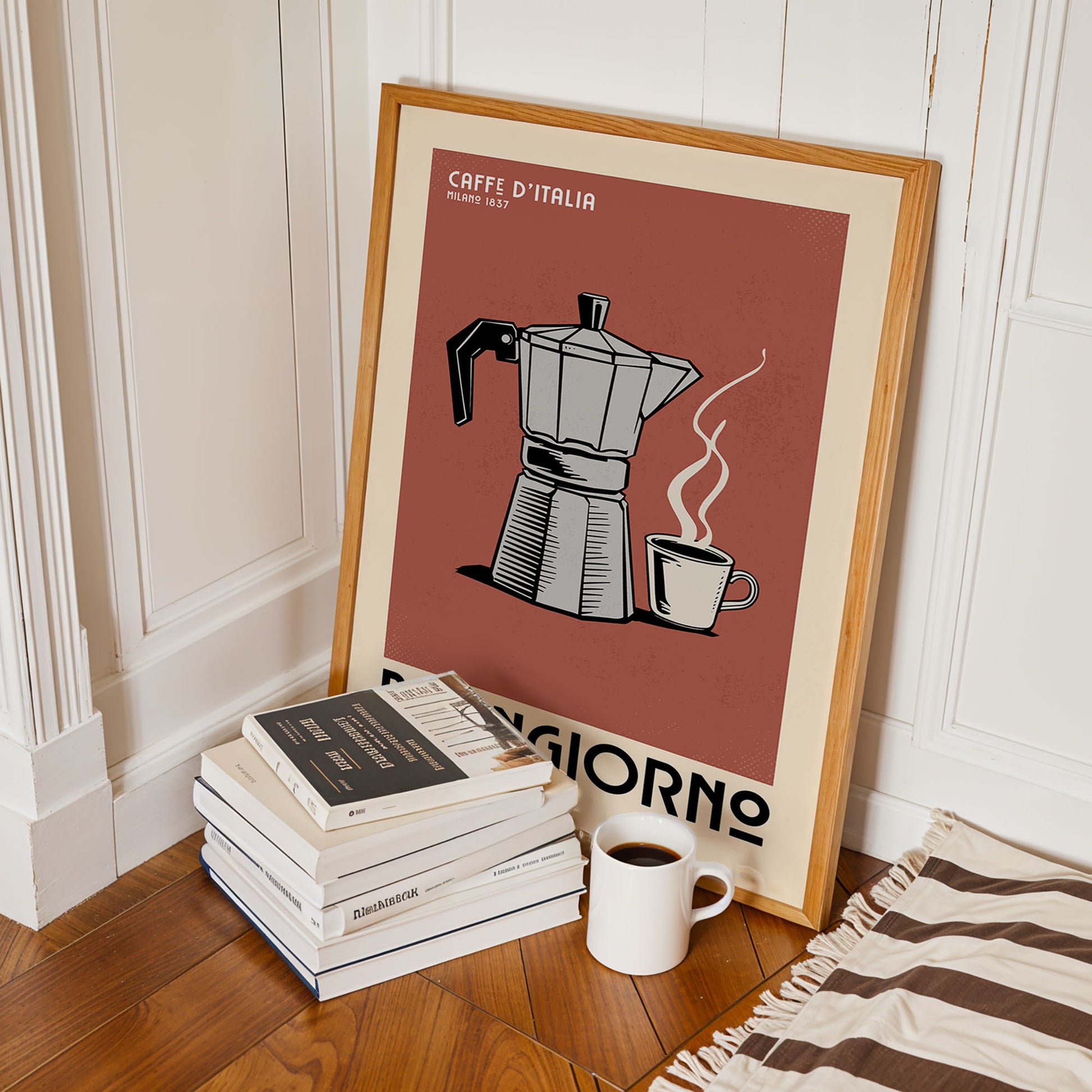 A framed poster of a coffee maker is leaning against a wall, with a stack of books and a cup of coffee nearby.