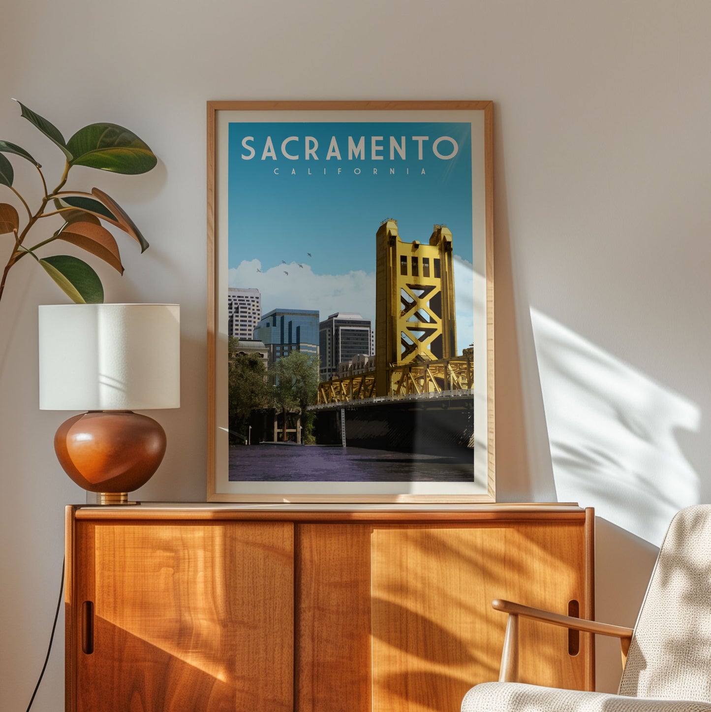 a framed poster of the Golden Gate Bridge in Sacramento, California, hanging on a wall next to a wooden cabinet and a lamp.