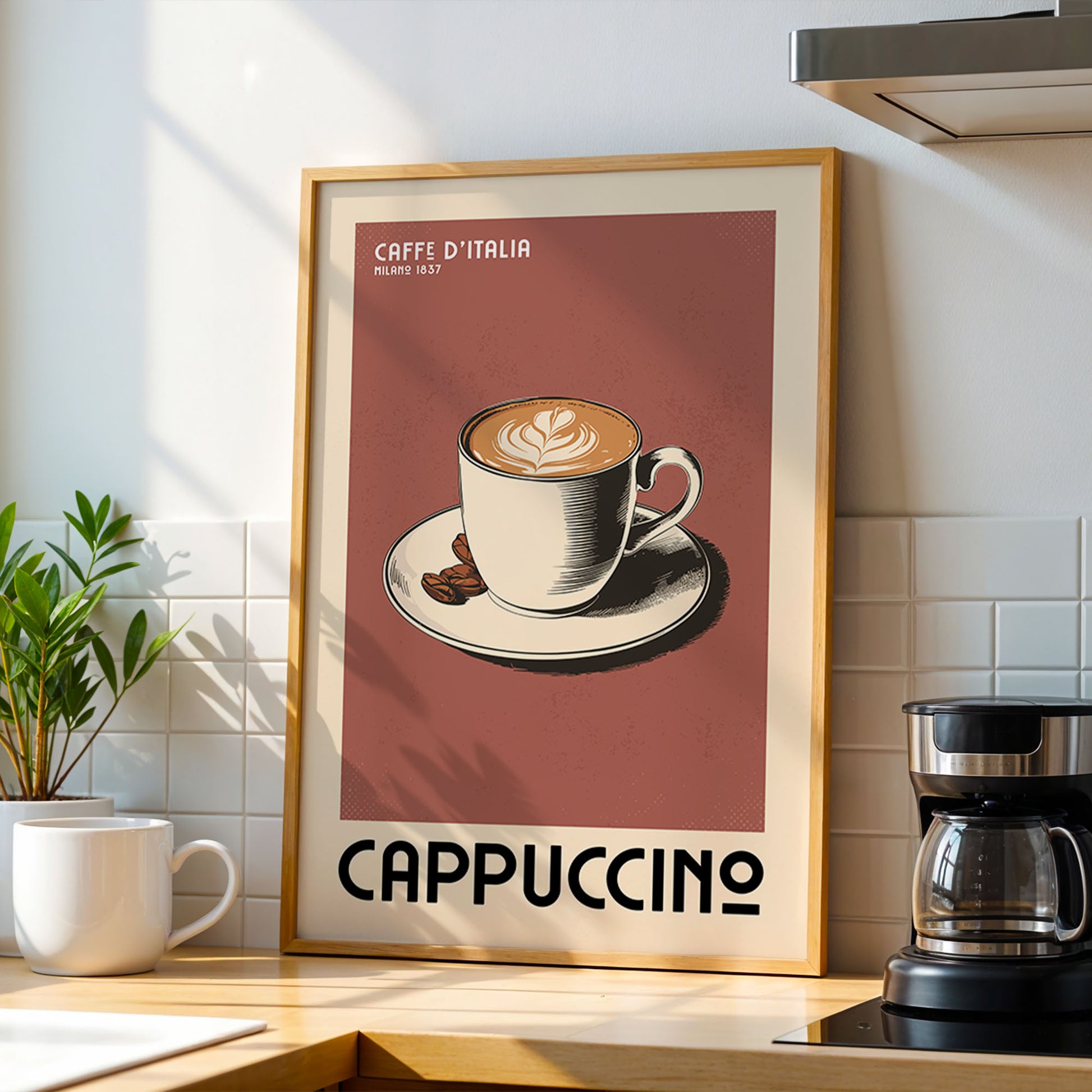 a framed poster of a cup of cappuccino, with the text "CAFFE D'ITALIA" and "MILANO 1637" printed on it. The poster is displayed on a kitchen counter, with a coffee maker and a potted plant visible in the background.
