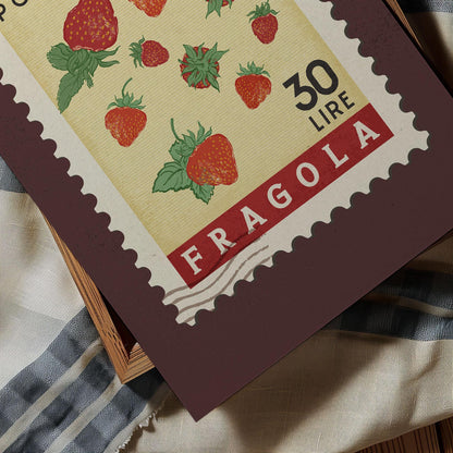 A close-up of a postage stamp featuring illustrations of strawberries, with the text &quot;FRAGOLA&quot; printed on it.